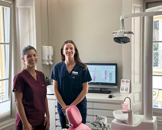 secrétaire dentaire souriante à l'accueil avec une cliente, dentiste neuchatel